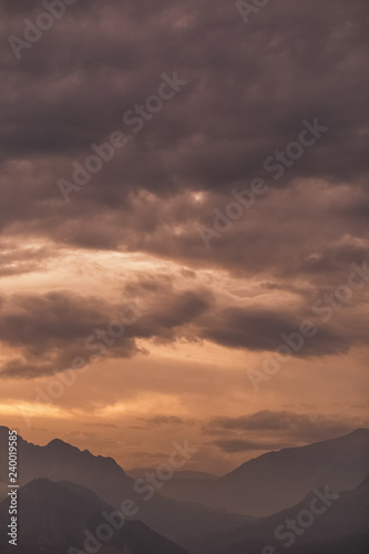 Beautiful golden sunset over peaks of mountains. Charming nature background. Vertical color photography.