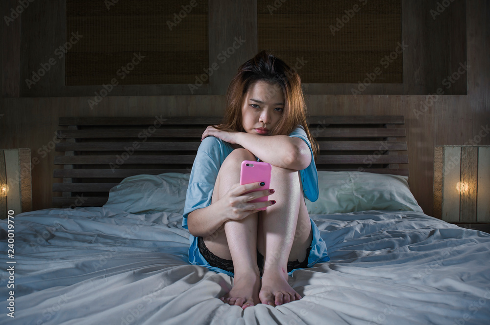 девушка сидит на кровати держит телефон и плачет