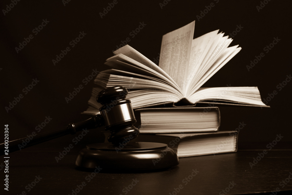 Judge gavel beside pile of books on wooden background Judge gavel beside pile of books on wooden background