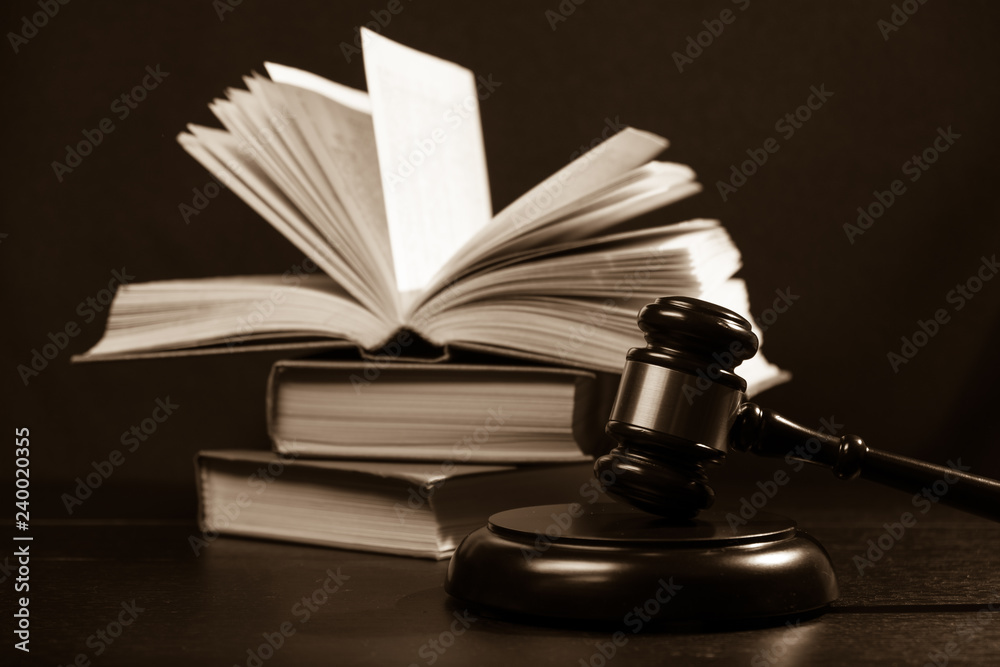 Judge gavel beside pile of books on wooden background Judge gavel beside pile of books on wooden background