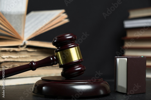 Judge gavel beside pile of books on wooden background