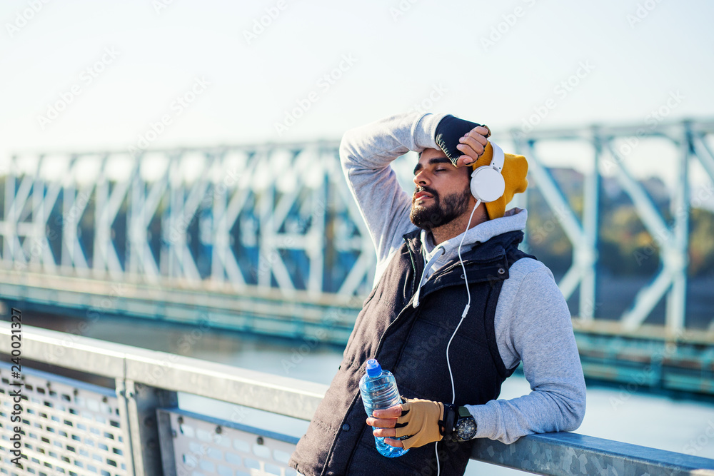 Tired male jogger resting and drink water