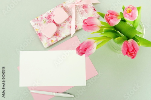 Valentine's day background. Flat lay, top view women's desk , blank mock up, gift, hearts and bouquet of pink tulips on grey background. Female workspace.Copy space.  © irenastar