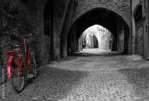 Jasnoczerwony rower przed ciemnymi łukami