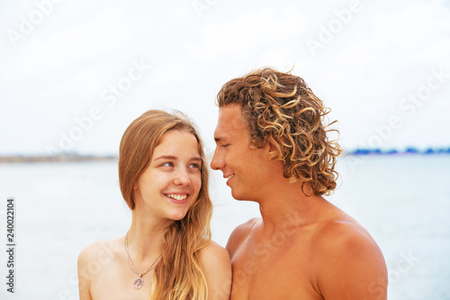 Portrait of young couple in love at beach and enjoying time being together. Young couple having fun on a sandy coast. © Georgii