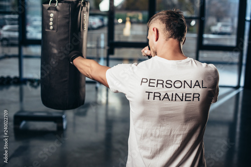 back view of personal trainer boxing with punching bag in gym © LIGHTFIELD STUDIOS