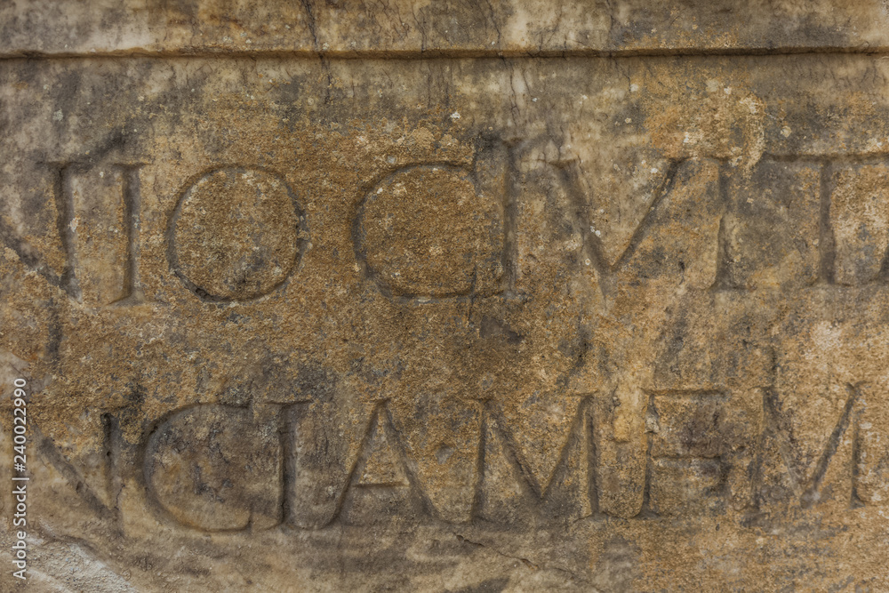 Real ancient letters сutted in stony wall of ancient architecture found during excavations of ancient ruins. Horizontal color photography.