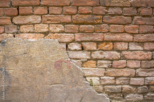 old damaged red gray brick wall with preserved plaster area. rough surface texture