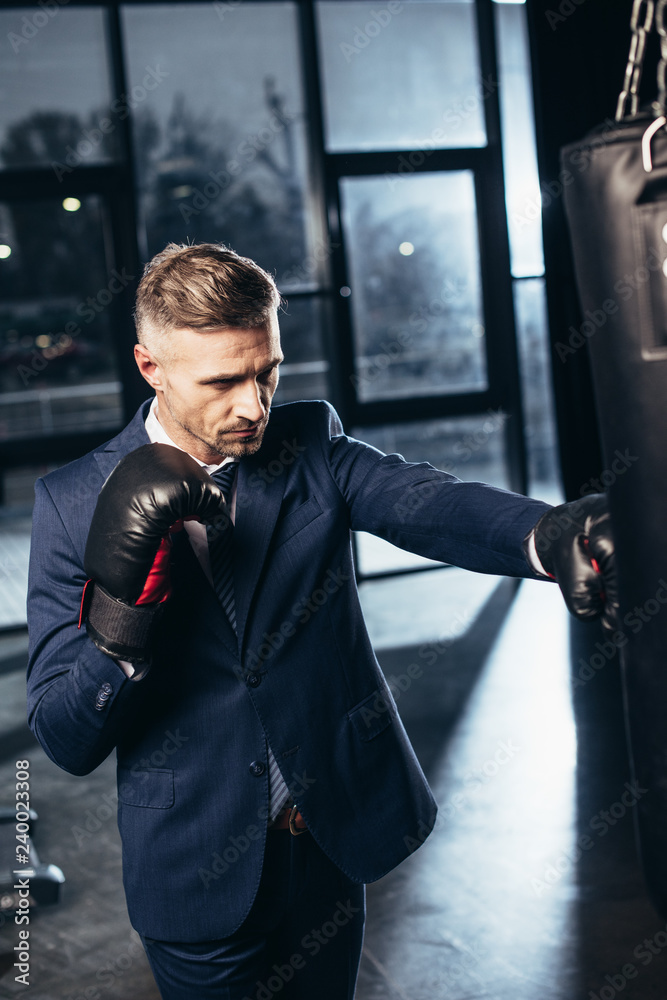 handsome businessman in suit boxing in gym