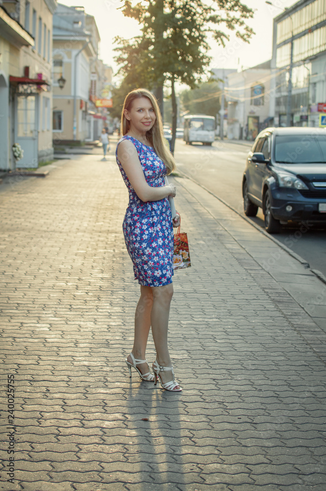 attractive girl in blue dress with shopping bags crossing a city street