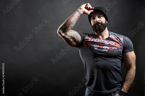 Uomo muscoloso con cappello e magliettafantasia su sfondo nero photo