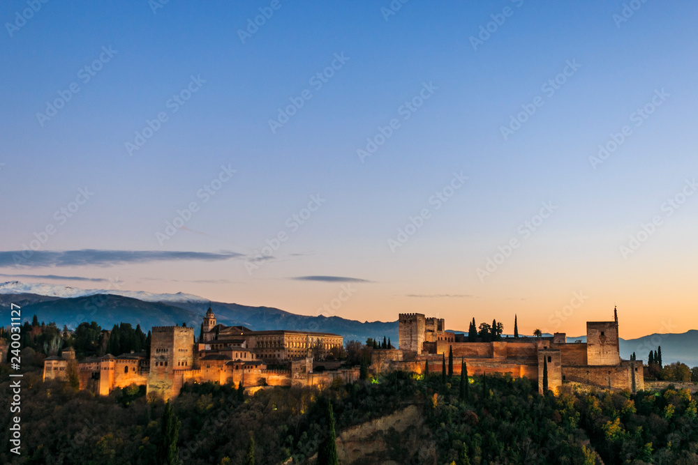 Alhambra Palace in Granada, Andalucia, Spain. Sierra Nevada mountains at the background. Golden hour at sunset. Space for text on the top