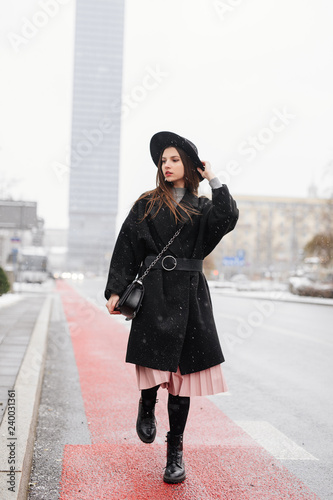 Young fashion woman walking on the city street wear black hat look around and smile to camera. Copy space. - Image