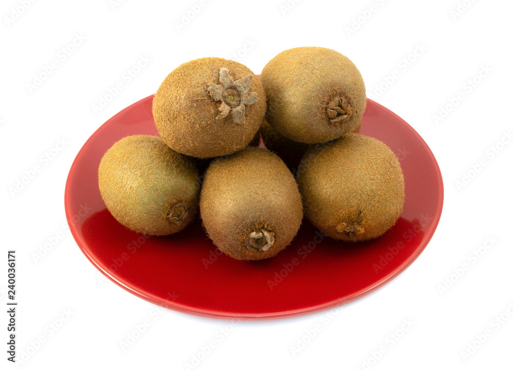 Whole kiwifruits with hairy skins piled on a red plate Whole kiwifruits with hairy skins piled on a red plate