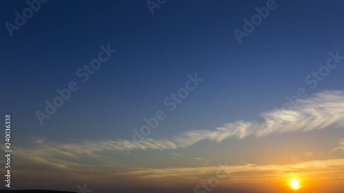4k timelapse clouds crossing the amazing sky over the sea or ocean at sunset. Sun rays emerge through the clouds. The clouds cross slowly from right to left and appear to be orange blue and purple. 