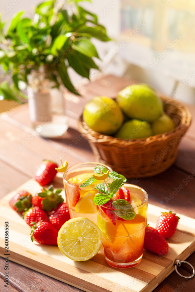Refreshing summer drink with lemon, strawberry and mint on wooden table Refreshing summer drink with lemon, strawberry and mint on wooden table