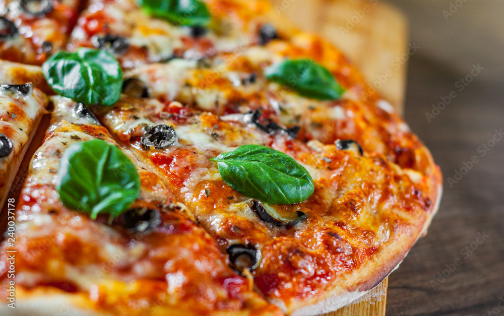 sliced Pizza with Mozzarella cheese, Tomatoes, pepper, olive, Spices and Fresh Basil. Italian pizza. Pizza Margherita or Margarita on wooden table background sliced Pizza with Mozzarella cheese, Tomatoes, pepper, olive, Spices and Fresh Basil. Italian pizza. Pizza Margherita or Margarita on wooden table background