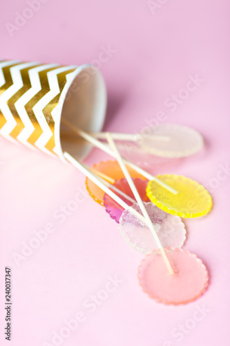 multi-colored lollipops on a pink background in a paper golden glass