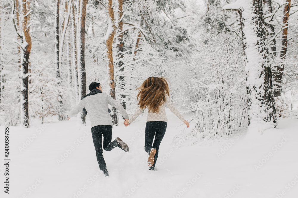 couple in love walking in the snowy forest, hugging, kissing and ...