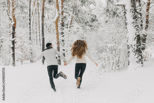  couple in love walking in the snowy forest, hugging, kissing and enjoying