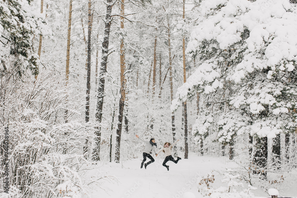 couple in love walking in the snowy forest, hugging, kissing and enjoying couple in love walking in the snowy forest, hugging, kissing and enjoying