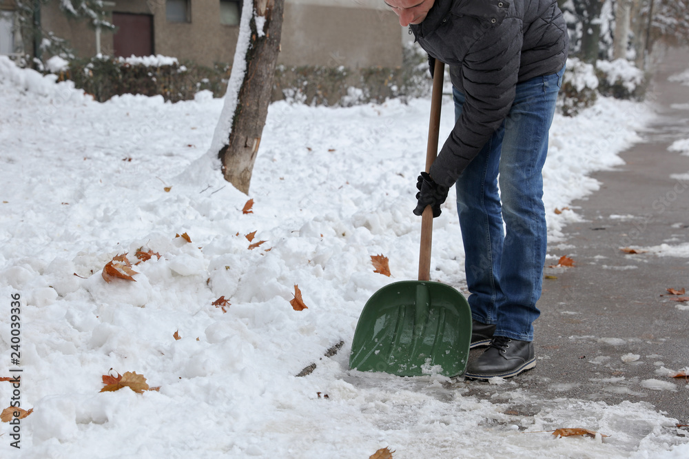Man cleaning snow from sidewalk in front of house. Man cleaning snow from sidewalk in front of house.