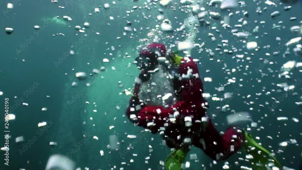 Underwater Santa Claus diver swims in water bubbles in New Year.