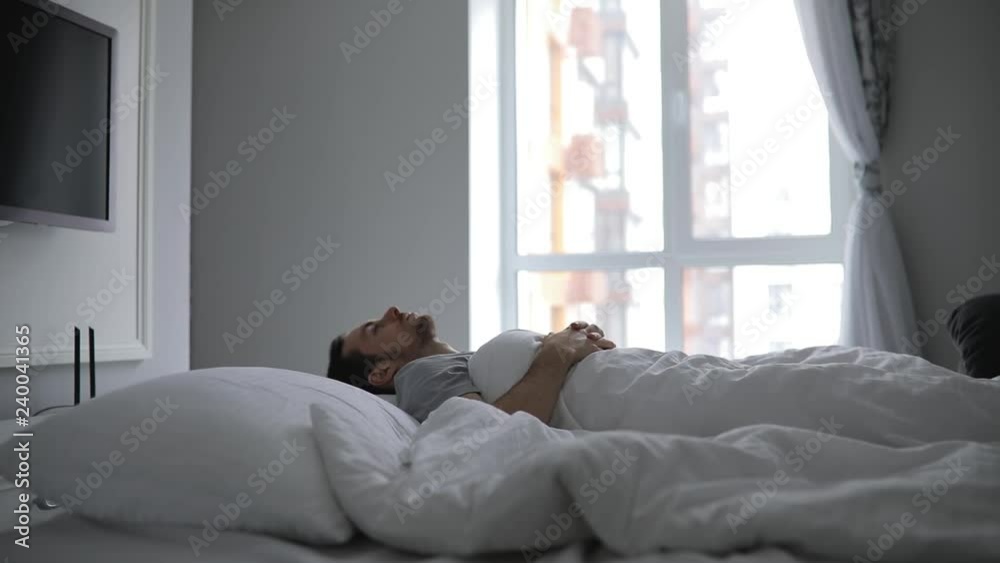 Man wake up in early morning on his bed, stretching arms Man wake up in early morning on his bed, stretching arms