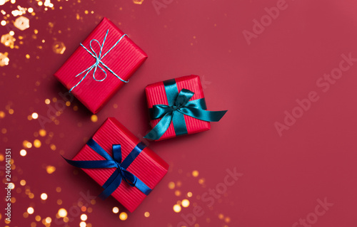 Christmas gift boxes wrapped in red paper on red background. Bright and festive Christmas concept. Top view, flat lay. Copy spce for text.