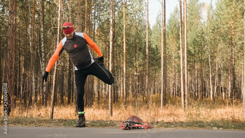 Training an athlete on the roller skaters. Biathlon ride on the roller skis with ski poles, in the helmet. Autumn workout. Roller sport. Adult man riding on skates. The athlete does the workout. photo