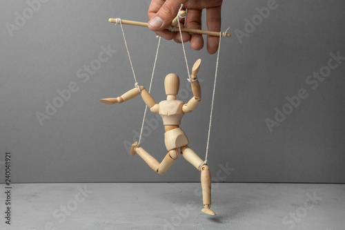 The puppeteer holds the doll by the rope. The doll does not obey the puppeteer.