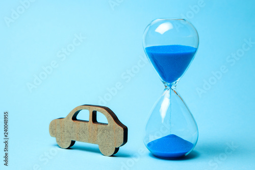 Depreciation or depreciation of the car over time. Wooden car and hourglass on blue background. Old car, second hand repair. photo