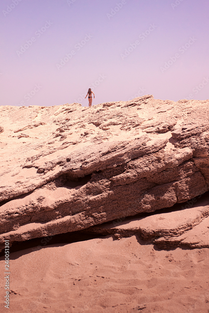 SILUETA DE MUJER SOBRE LAS ROCAS DESGASTADAS EN LA PLAYA SILUETA DE MUJER SOBRE LAS ROCAS DESGASTADAS EN LA PLAYA