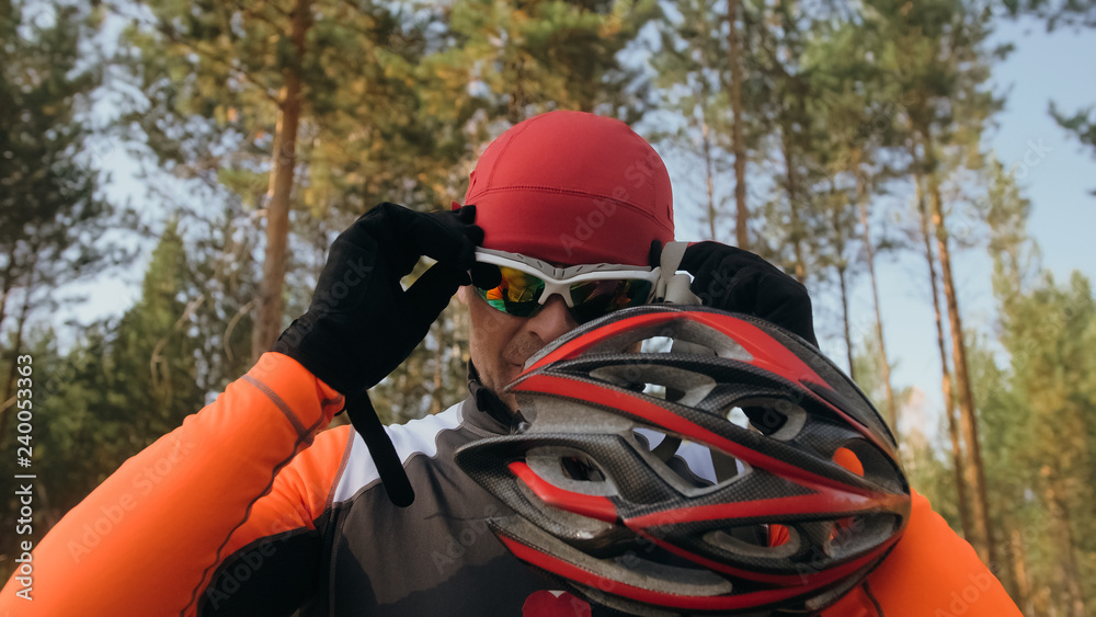 Training an athlete on the roller skaters. Biathlon ride on the roller skis with ski poles, in the helmet. Autumn workout. Roller sport. Adult man riding on skates. Athlete is getting ready to start.