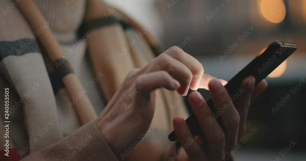 Close up of the smartphone in hands of the Caucasian woman and she tapping or texting on it. Outside.