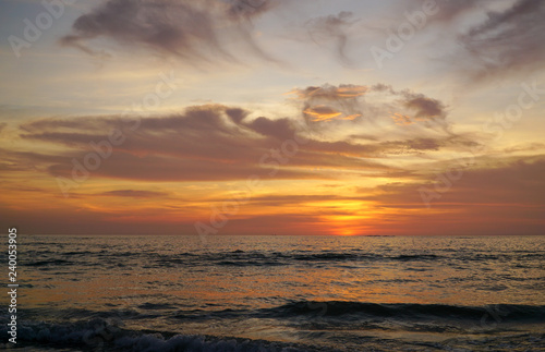 Colorful ocean beach sunset with a few clouds