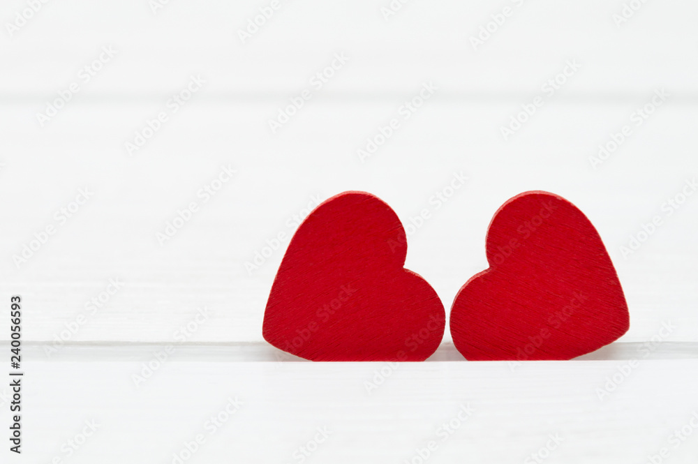 Fototapeta premium Two red wooden hearts on white wooden background. Valentine's day or Love concept.