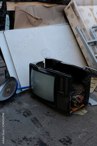 Poste télévision cathodique cassé déposé avec ordure sur le trottoir photo
