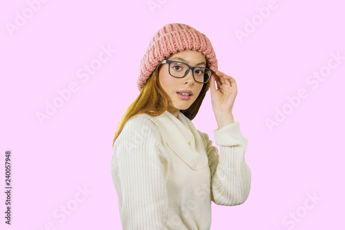 Attractive young red-haired girl with glasses looking at the camera on an isolated background