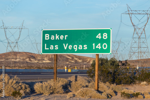 Late afternoon view of Las Vegas 140 miles and Baker 48 miles highway sign on I-15 near Barstow in California.  
