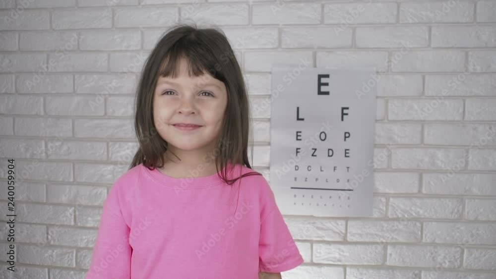 Kid at consultation alternately closes eyes. The little girl at the ophthalmologist covers her eyes with her hands. Kid at consultation alternately closes eyes. The little girl at the ophthalmologist covers her eyes with her hands.