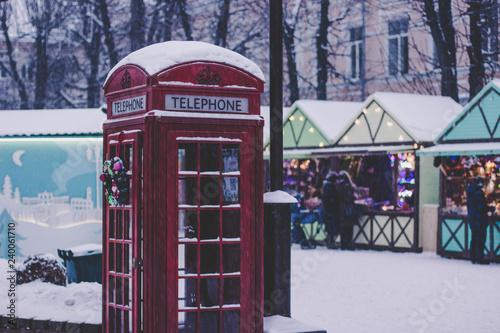 winter Christmas holidays concept outdoor urban street view with red classic phone booth on winter fair unfocused background with people in snowing frost weather time 