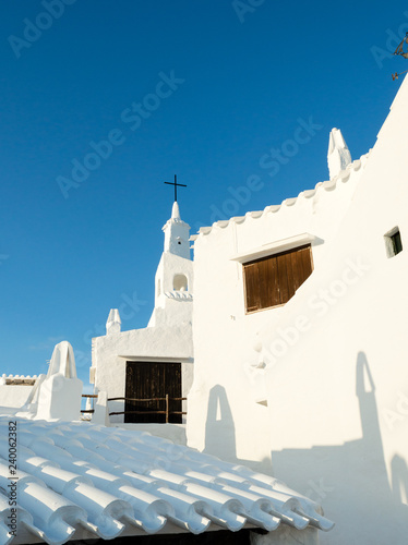 View of a typical church with white walls and roof of the fishing village Binibeca Menorca Spain