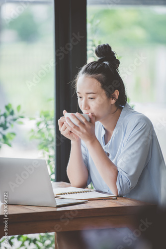 Asian girls drinking coffee on the desk at home.