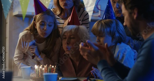 Wallpaper Mural Caucasian happy grandmother sitting at home surrrounded by family and blowing candles on the cake. Inside. Torontodigital.ca