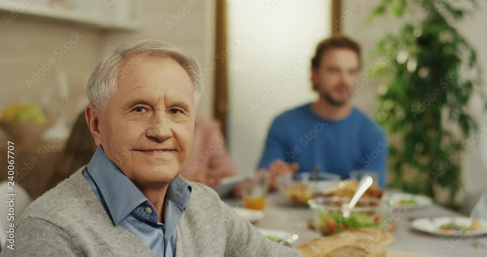 Portrait of the senior Caucasian man sitting at the family dinner table and smiling to the camera. Close up. Portrait of the senior Caucasian man sitting at the family dinner table and smiling to the camera. Close up.