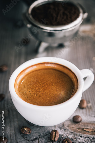 Fresh tasty espresso cup of hot coffee with coffee beans and Coffee maker on wood table background