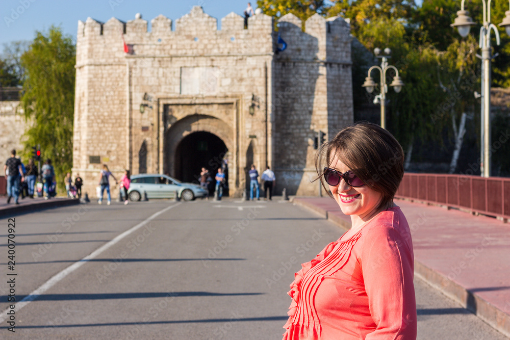 Young Woman With Sunglasses Standing on the Bridge in the Middle of the Street and Smiling