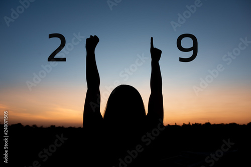 Silhouette of happy woman with New year 2019 concept on sunset background.