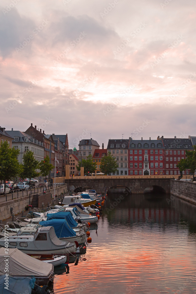 Copenhagen during sunrise with motorboats and buildings reflection, Denmark. City skyline with a view on canal.